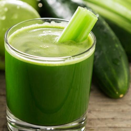 A vibrant green juice in a glass with a fresh celery stalk, surrounded by cucumbers and a lime, showcasing a healthy and refreshing juice recipe from a wellness ebook.