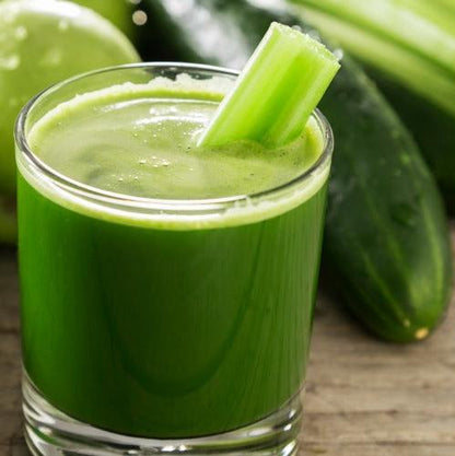 A vibrant green juice in a glass with a fresh celery stalk, surrounded by cucumbers and a lime, showcasing a healthy and refreshing juice recipe from a wellness ebook.